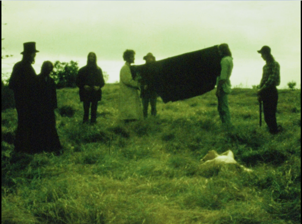 The Priest (John Pearce) and his helpers collect the body of Jim Beiers in the Box